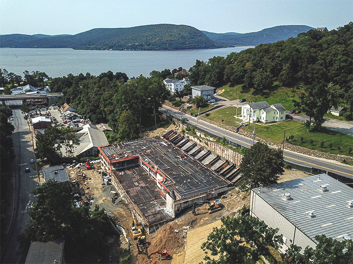 Foundation floors have been prepared for continued construction. Background shows surrounding properties and the Hudson River.